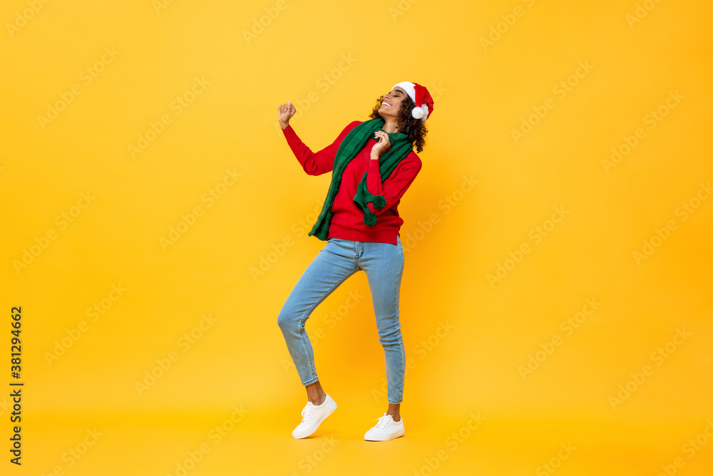Full length portrait of fun happy woman in Christmas attire dancing on isolated yellow studio background