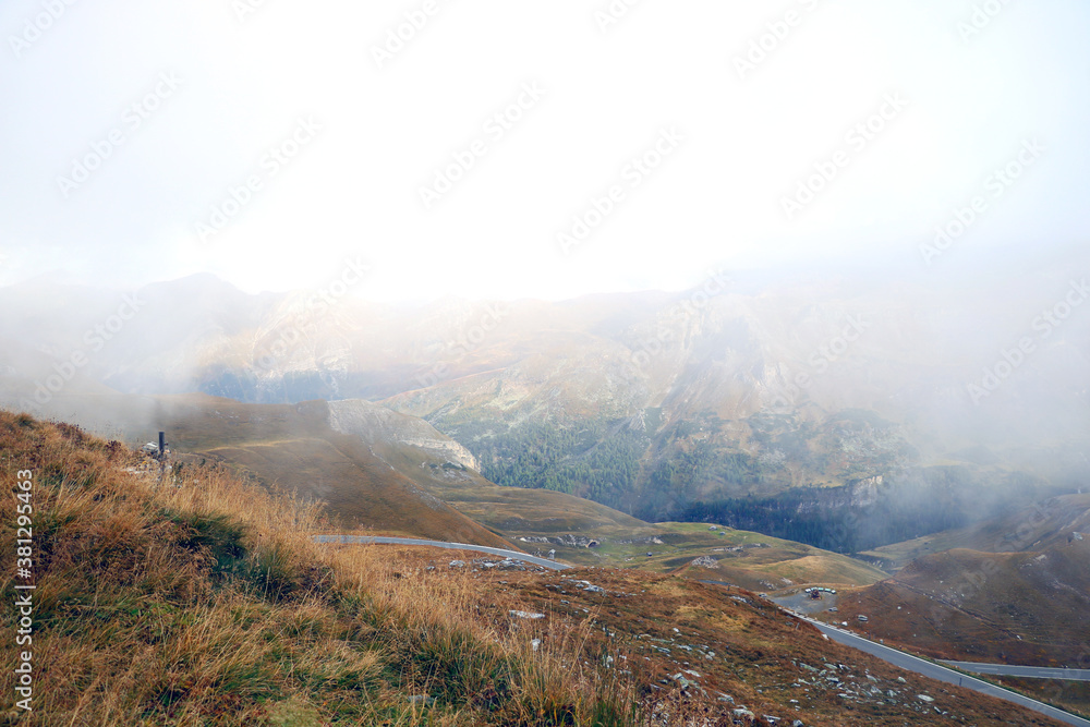 Aerial view of a winding road in the mountains on a foggy autumn morning. Alps. Danger when driving in fog.