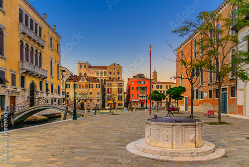 Campo San Vio with Palazzo Cini and Palazzo Barbarigo palaces, stone well and bridge across narrow water canal, buildings on Grand Canal waterway in Venice historical city centre background, Italy