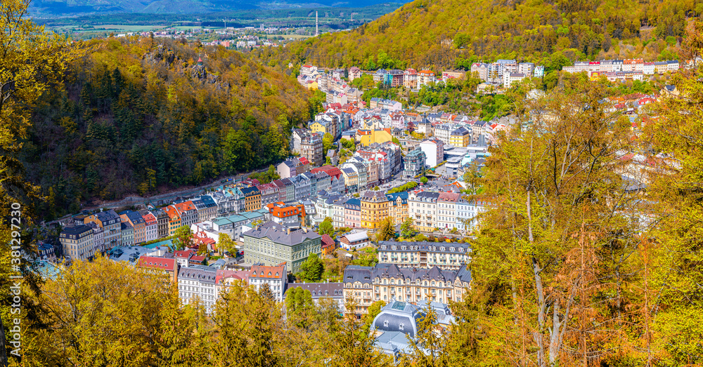 Karlovy Vary city aerial panoramic view with colorful multicolored buildings and spa hotels in historical centre. Panorama of Karlsbad town and Slavkov Forest hills with trees on slope in autumn