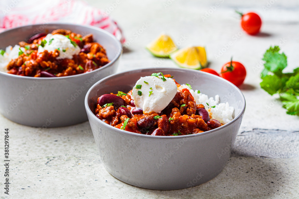 Chili con carne with rice in gray bowl. Beef stew with beans in tomato sauce with sour cream and rice. Traditional Mexican food concept. Chili con carne with rice in gray bowl. Beef stew with beans in tomato sauce with sour cream and rice. Traditional Mexican food concept.
