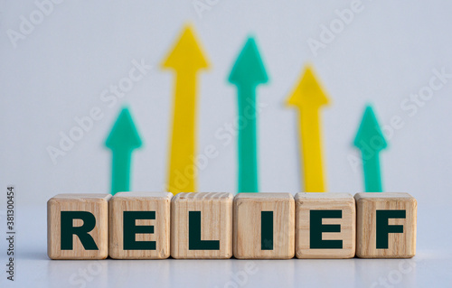 RELIEF - word on wooden cubes on a light background with arrows up