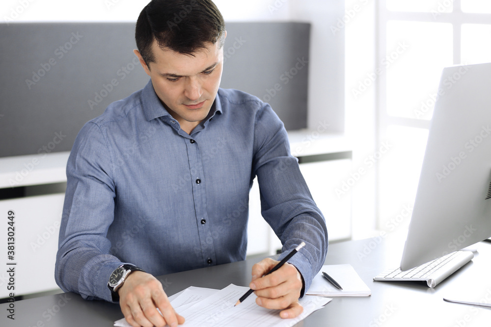 Businessman working with computer in modern office. Headshot of male entrepreneur or company director at workplace. Business concept Businessman working with computer in modern office. Headshot of male entrepreneur or company director at workplace. Business concept