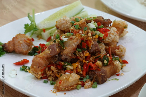Stir fried pork belly slice with chilli and salt on a white plate. It is delicious and slightly spicy. Thaifood 