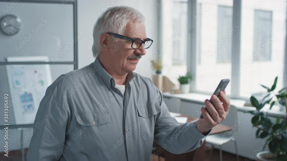 Medium portrait shot of modern Caucasian senior man wearing eyeglasses surfing Internet using smart phone Medium portrait shot of modern Caucasian senior man wearing eyeglasses surfing Internet using smart phone