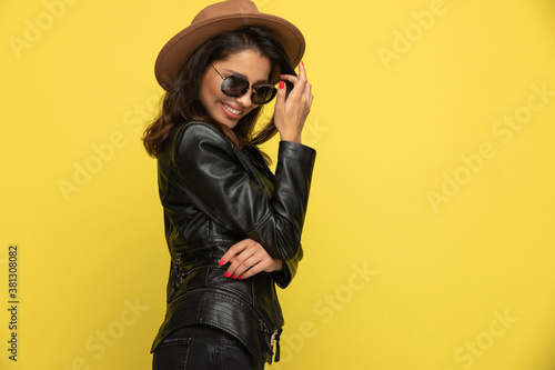 timid young girl in leather jacket arranging hair and smiling