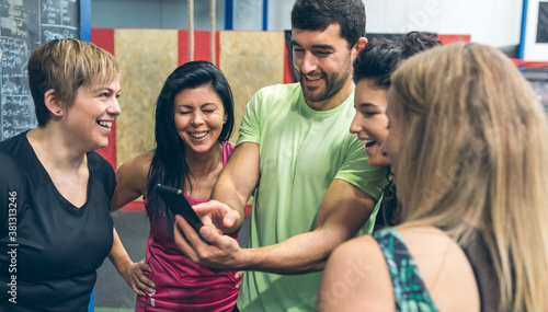 Group of athletes laughing looking at the mobile of a gym mate