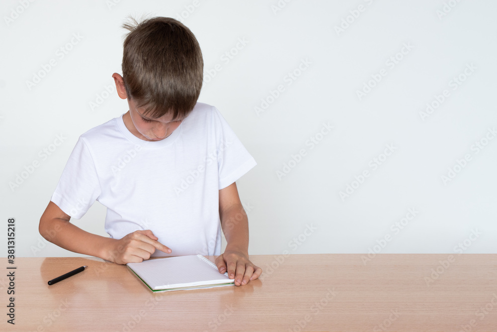 Back to school. Thinking child boy looking in a notebook or book, sitting at the table and doing homework Back to school. Thinking child boy looking in a notebook or book, sitting at the table and doing homework