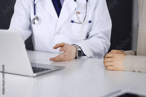 Doctor and patient woman discussing something while sitting in clinic and using laptop. Best medical service in hospital  medicine  pandemic stop