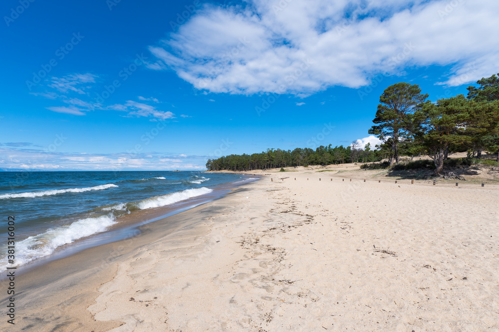 A beautiful sandy beach with a coniferous forest in the bay of the village of Goryachinsk, a popular resort in Buryatia. Summer. Eastern Siberia, Russia