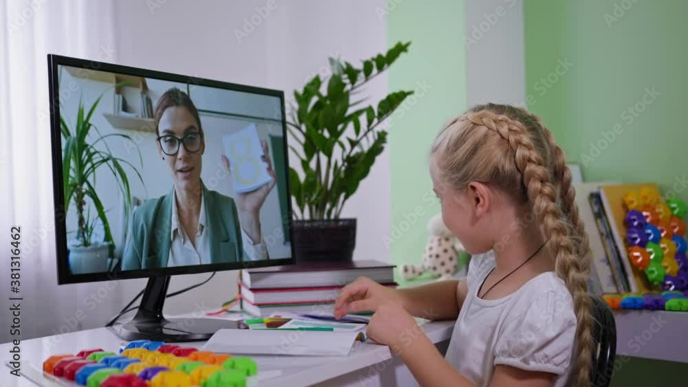 homeschooling kid, pupil girl learns through online communication with the teacher while sitting with computer in room in coronavirus times homeschooling kid, pupil girl learns through online communication with the teacher while sitting with computer in room in coronavirus times