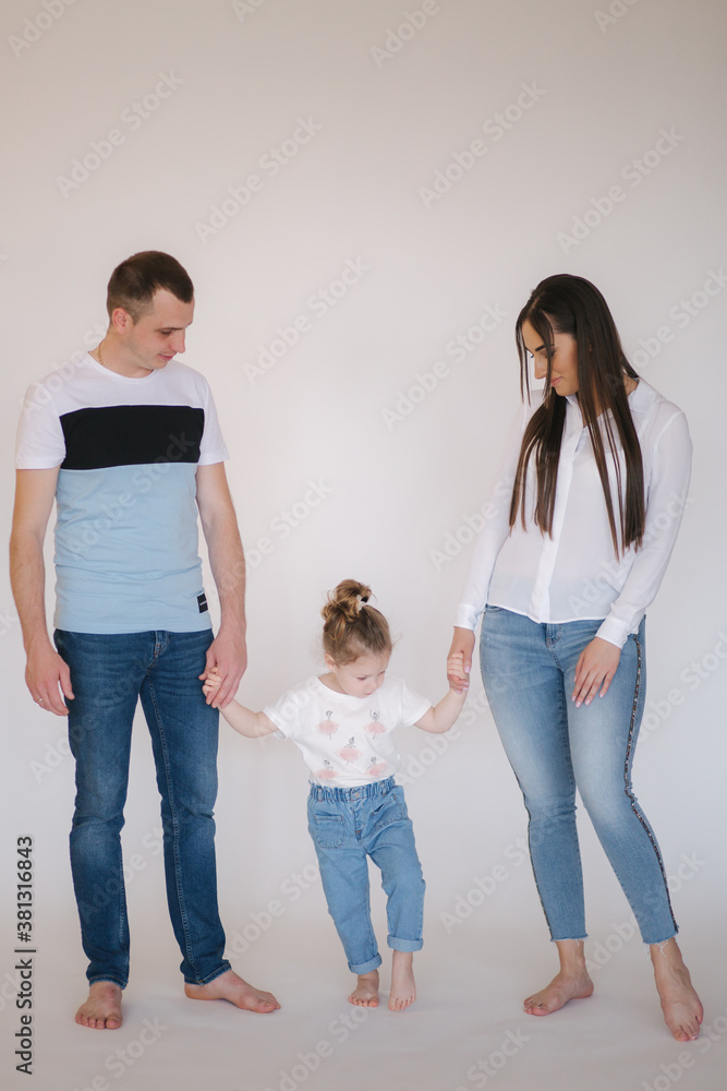 Young family in studio. Mom dad and little daughter in casual style has photosession Young family in studio. Mom dad and little daughter in casual style has photosession