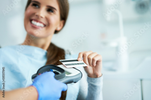 Adult woman paying for visit in dentist office photo