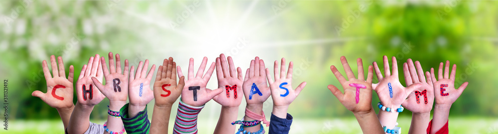 Children Hands Building Colorful English Word Christmas Time. Sunny Green Grass Meadow As Background