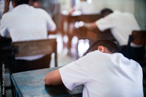Tired uniform student sleeping in a exam test classroom