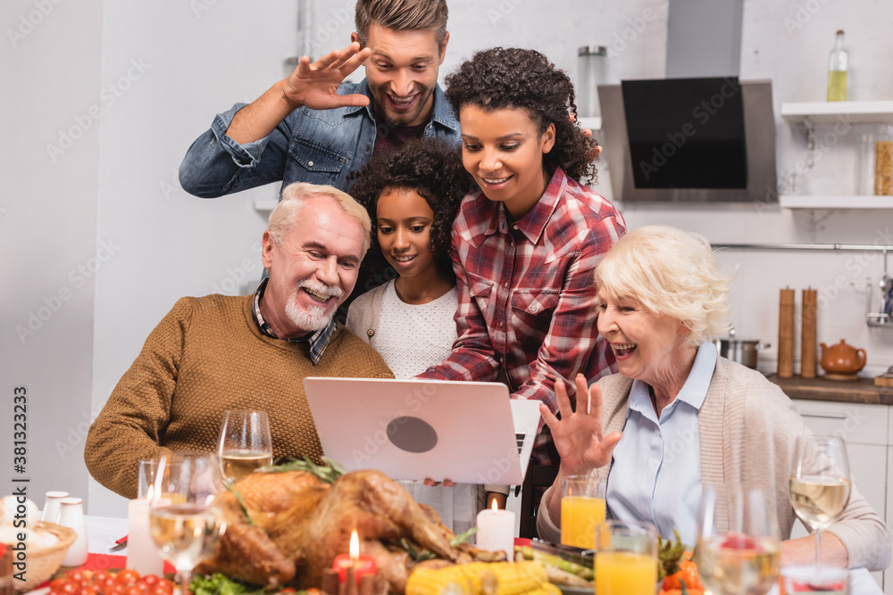 Φωτογραφία Selective focus of multicultural family having video call on laptop near food du