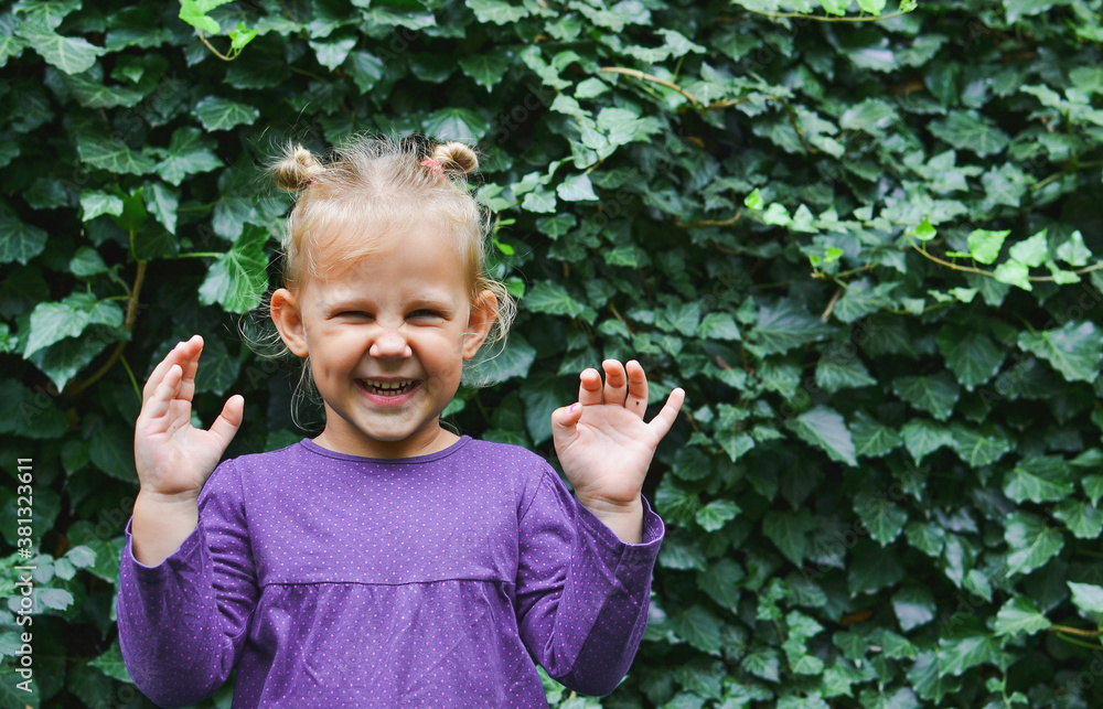 Portrait of a beautiful child against a background of green leaves. The child is smiling looking into the camera. Portrait of a beautiful child against a background of green leaves. The child is smiling looking into the camera.