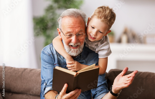 . Cheerful grandfather and grandson reading book together. photo
