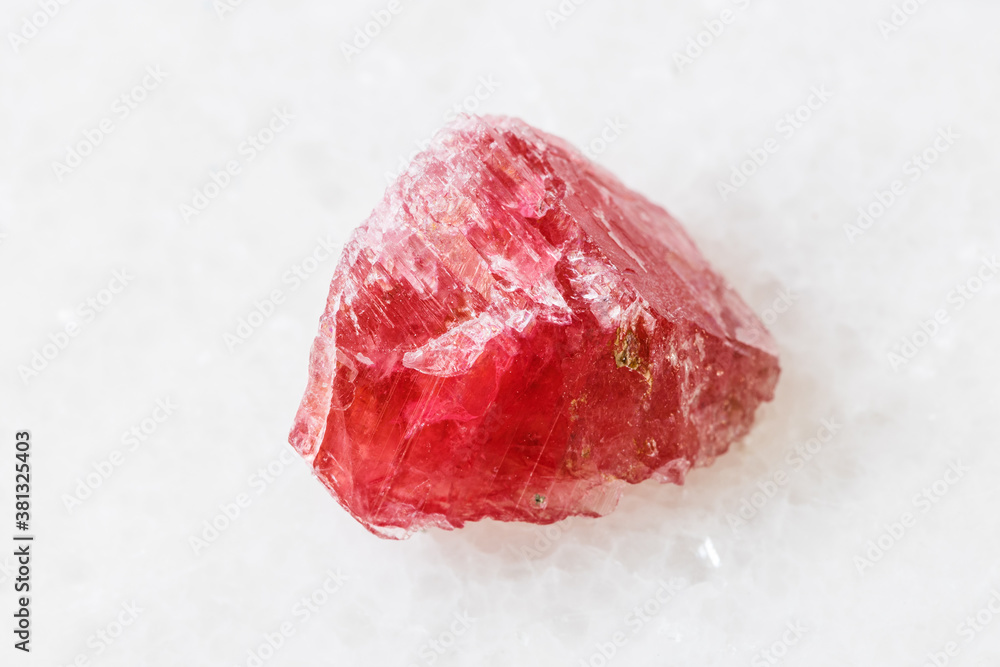closeup of sample of natural mineral from geological collection - rough Rhodonite crystal on white marble background from Morro da Mina mine, Conselheiro Lafaiete, Minas Gerais, Brazil closeup of sample of natural mineral from geological collection - rough Rhodonite crystal on white marble background from Morro da Mina mine, Conselheiro Lafaiete, Minas Gerais, Brazil