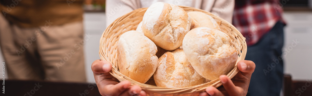 Panoramic crop of african american child holding basket with buns at home Panoramic crop of african american child holding basket with buns at home
