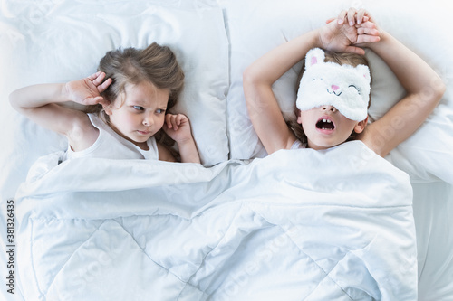 Little girls sleep in bed. One is snoring hard,sister is plugging ears with fingers. Early morning wake up,rise to kindergarten,school. Bedtime,sweet dreams.Kids correct daily routine for child