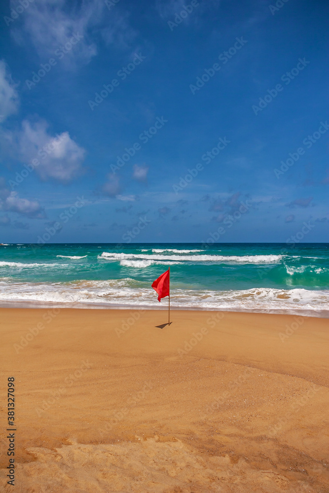 Warning sign of a red flag flying at a beautiful beach with a blue sky and a turquoise sea, Phuket Islands, Thailand, Asia. Warning sign of a red flag flying at a beautiful beach with a blue sky and a turquoise sea, Phuket Islands, Thailand, Asia.