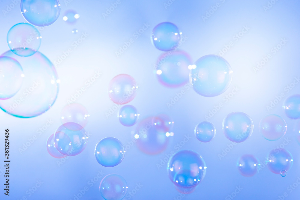 Colorful soap bubbles float natural background.