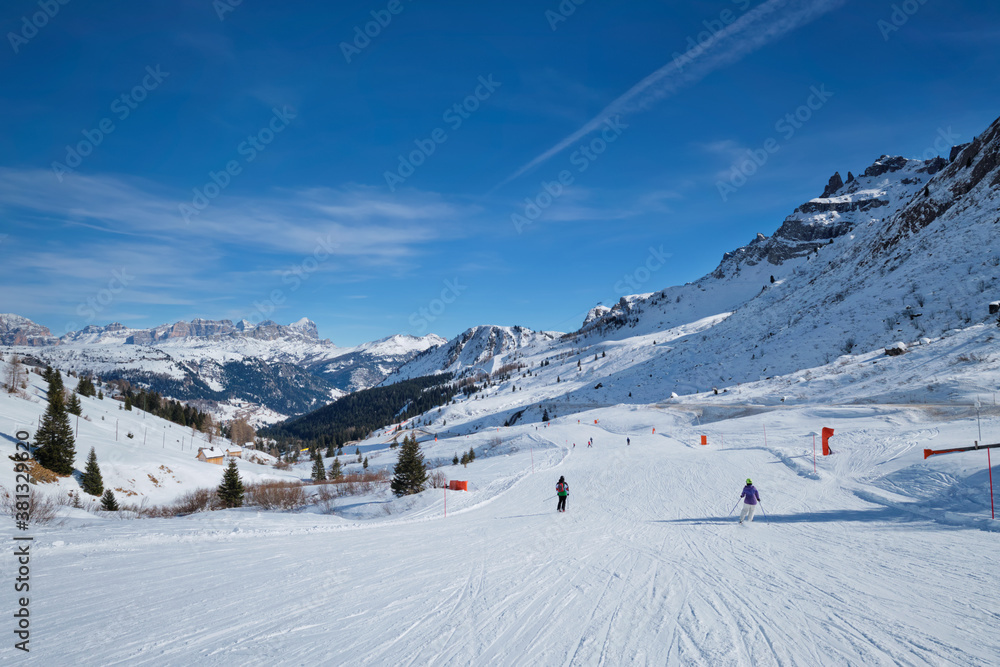 View of a ski resort piste with people skiing in Dolomites in Italy. Canazei, Italy