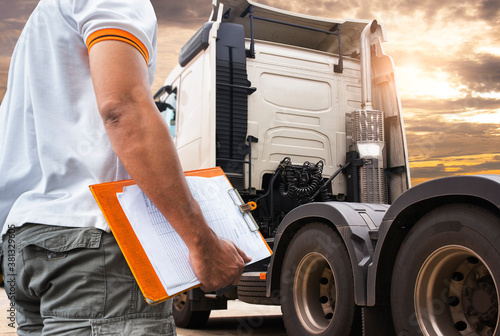 Truck inspection maintenance and repairing. A truck driver holding clipboard his checking safety to before driving semi truck. photo