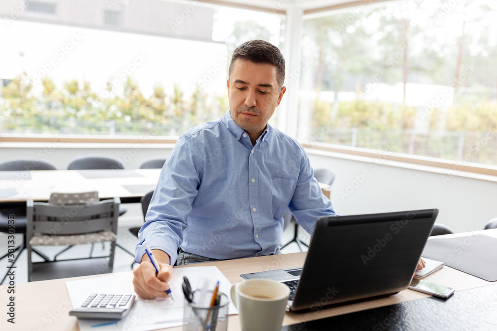remote job, business and people concept - middle-aged man with calculator, papers and laptop computer working at home office remote job, business and people concept - middle-aged man with calculator, papers and laptop computer working at home office