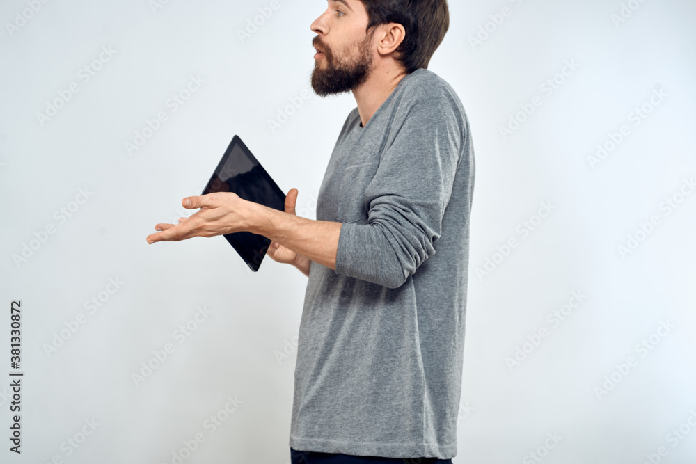 A man with a tablet in his hand internet technology communication gray jacket light background A man with a tablet in his hand internet technology communication gray jacket light background