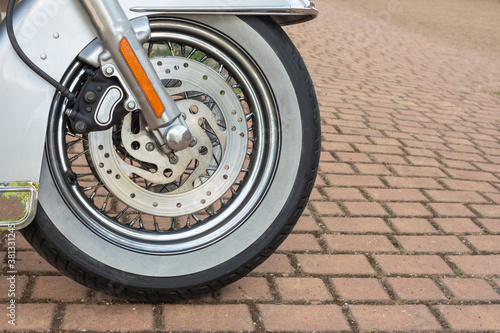 Closeup of the tire of a modern motorcycle parked outdoors under the sunlight