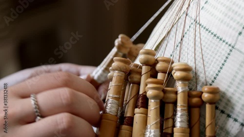 Video detail of bobbin lace handcrafting. Woman hands braiding threads to make a pattern.