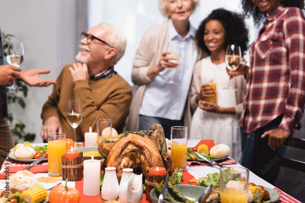 selective focus of multiethnic family celebrating thanksgiving at table with festive dinner