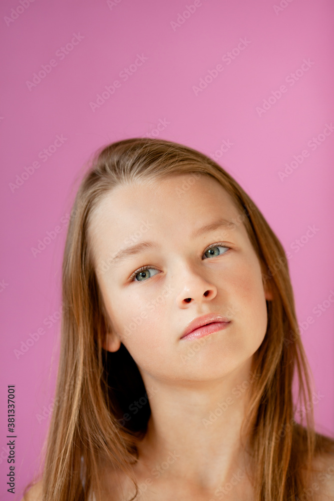 portrait of a gentle 9-year-old long-haired girl in a light T-shirt against a lilac wall