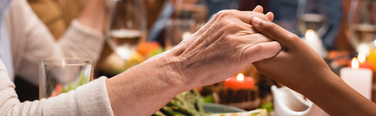 Panoramic crop of african american girl and senior woman holding hands on thanksgiving