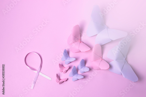 Pink bow fights breast cancer next to pink paper butterflies that seem to be flying on pink background