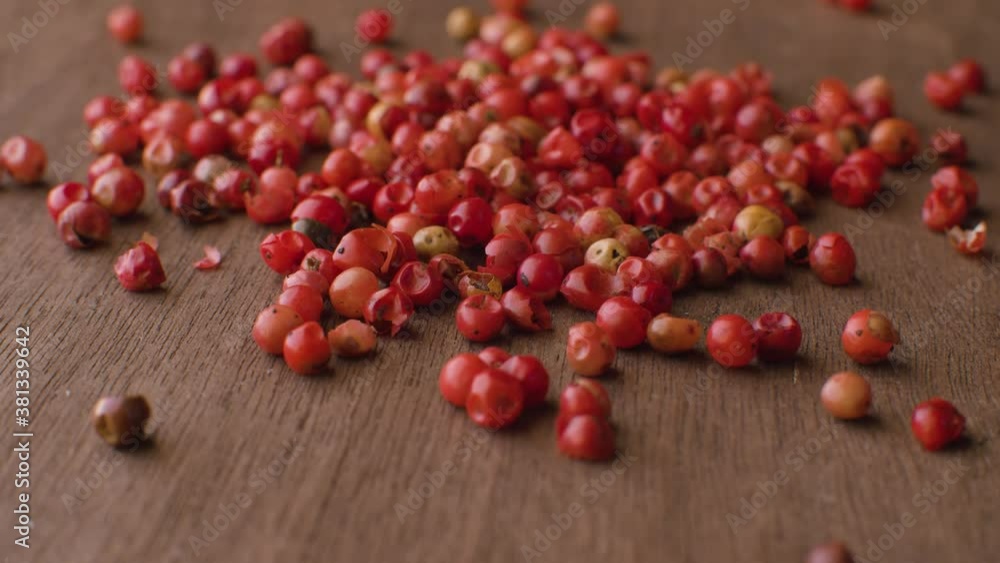 Macro shot of red peppercorns mix - aromatic spice - on the wooden table.. Extreme close up, camera slowly moving on slider Macro shot of red peppercorns mix - aromatic spice - on the wooden table.. Extreme close up, camera slowly moving on slider