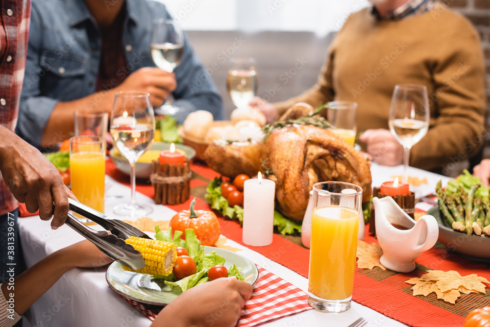 cropped view of multicultural family celebrating thanksgiving day at served table