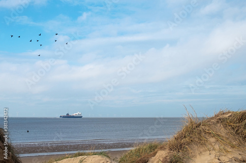 Tableau sur toile Canada geese flying over Crosby beach, Liverpool, known as Another Place, where