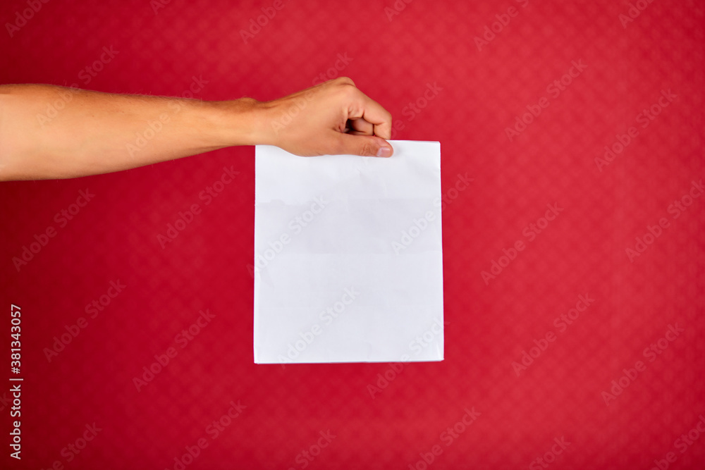 Closeup courier hand holding grocery paper bag, delivery service, studio shot isolated on red background, copy space.. Closeup courier hand holding grocery paper bag, delivery service, studio shot isolated on red background, copy space..