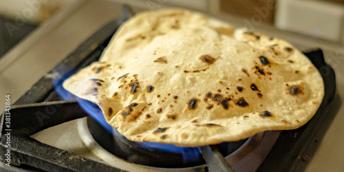 Wheat chapati or roti cooked on fire using a gas stove