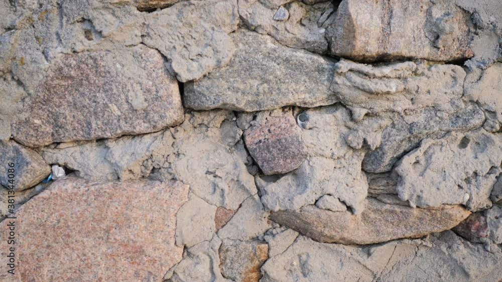 Texture of old stones of various forms with seams. Close up of shabby masonry. Stone wall from uneven different ancient friable cobblestones. Texture of old stones of various forms with seams. Close up of shabby masonry. Stone wall from uneven different ancient friable cobblestones.