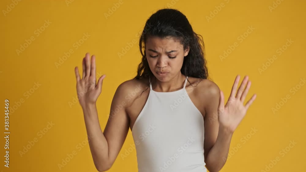 A cheerful emotional young woman is dancing isolated over yellow background A cheerful emotional young woman is dancing isolated over yellow background