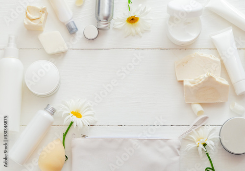 Set white cosmetic products FRAME on wooden table with flowers. Beauty skin care hair treatment cosmetic serum oil moisturizer skin cream body butter soap lotion shampoo. Flat lay copy space