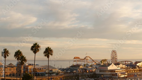 Classic ferris wheel, amusement park on pier in Santa Monica pacific ocean beach resort. Summertime California aesthetic, iconic view, symbol of Los Angeles, CA USA. Sunset golden sky and attractions