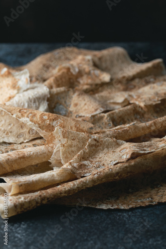 Homemade thin armenian pita bread (lavash) lies on a dark blue stone background. Selective focus.