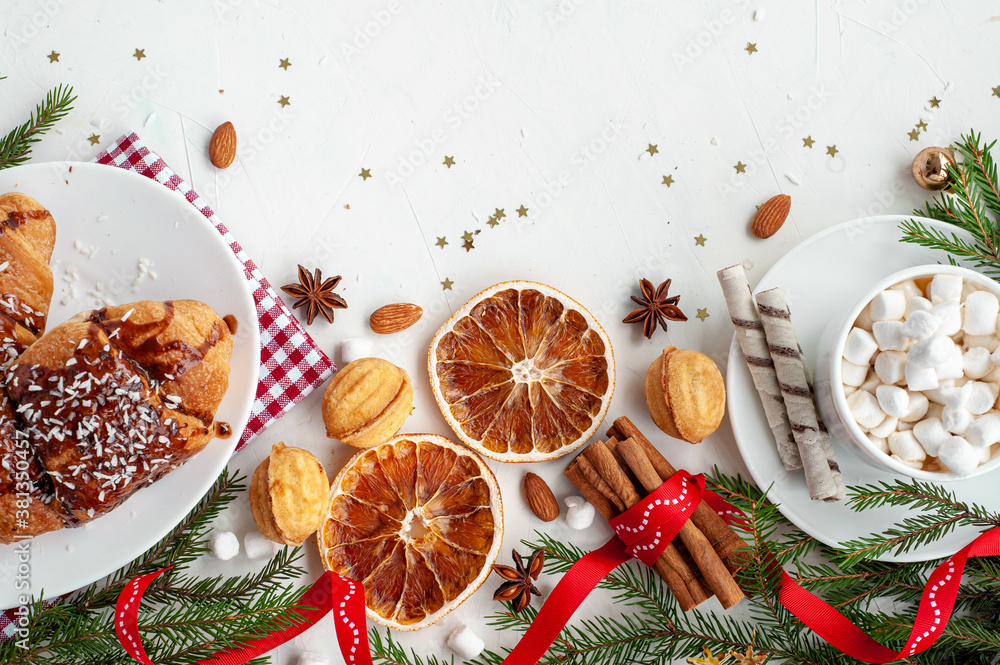 Christmas breakfast. Christmas morning. A cup of cocoa with marshmallows and croissants on a light concrete background with a branch of decorated Christmas tree. View from above. Christmas breakfast. Christmas morning. A cup of cocoa with marshmallows and croissants on a light concrete background with a branch of decorated Christmas tree. View from above.