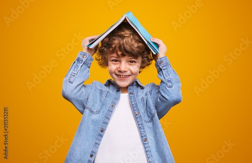 Obraz na płótnie Happy schoolboy hiding under textbook