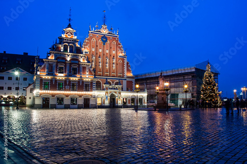 View of famous House of the Black Heads illuminated at night and Christmas tree in Riga, Latvia. Night view of Riga Town Hall Square and Roland's Statue with Christmas decoration.